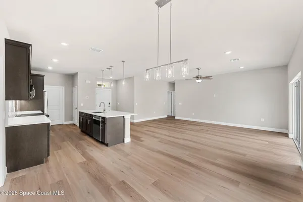 a large kitchen with kitchen island a stove a sink dishwasher a refrigerator and white cabinets with wooden floor