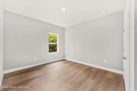 an empty room with wooden floor and window