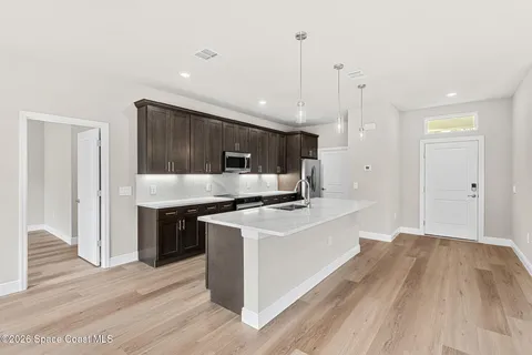a kitchen with stainless steel appliances granite countertop a sink a stove and a wooden floors