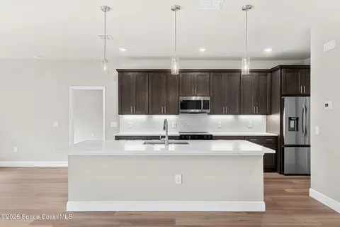 a kitchen with kitchen island stainless steel appliances a sink a counter top space and cabinets