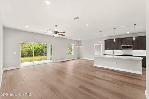 a view of an empty room with a window and wooden floor
