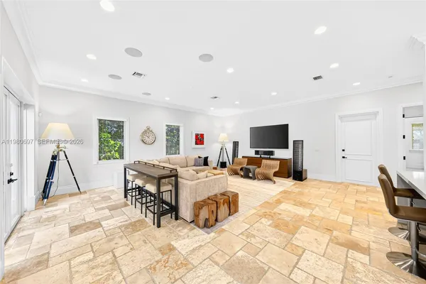 a large white kitchen with a white kitchen island a stove a sink a dining table and chairs