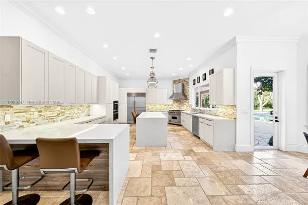 a kitchen with a sink a stove a center island and stainless steel appliances