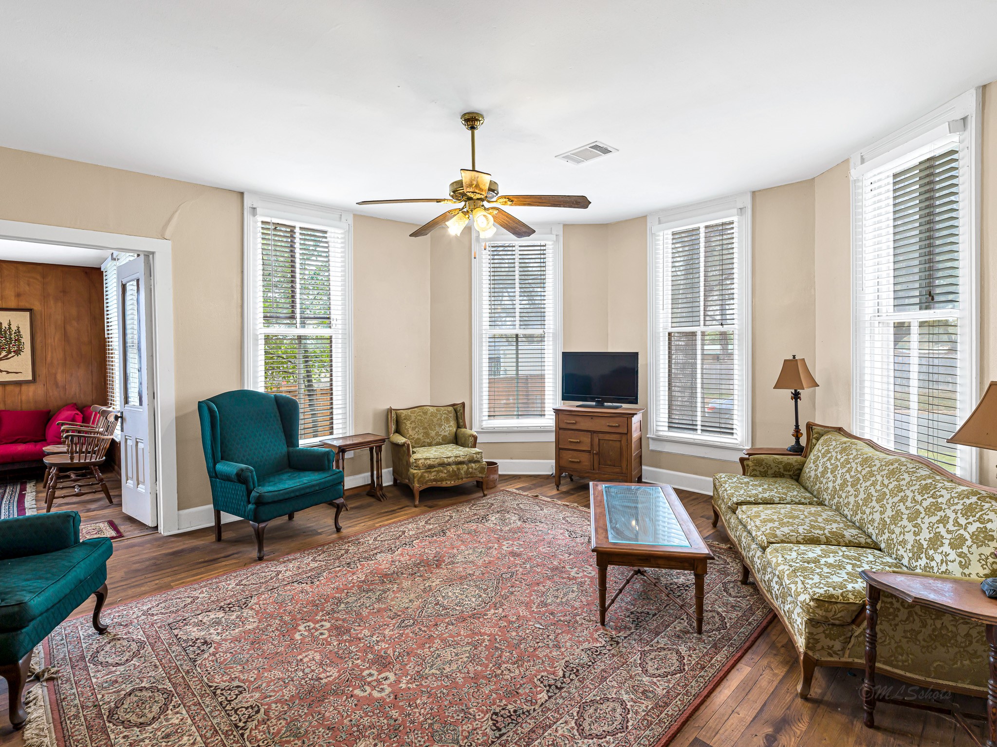 26 West Austin Street Bellville, TX 77418 - Photo 7 of 40 The living room features: Believed to be original hardwood floors and a distinctive half-octagonal bay with four windows, filling the space with natural light and highlighting the home’s historic character.
