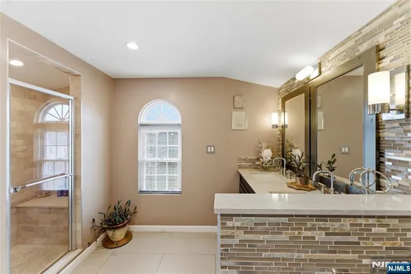 a bathroom with a granite countertop sink a large mirror and a shower
