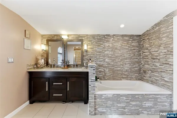 a bathroom with a granite countertop sink a mirror and a bathtub