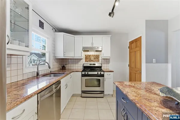 a kitchen with stainless steel appliances granite countertop a stove sink and cabinets