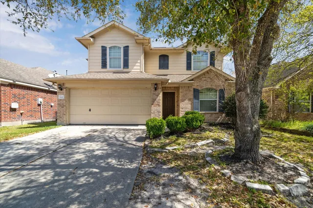 a view of a house with a yard and large tree