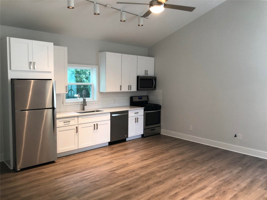 a kitchen with stainless steel appliances a refrigerator sink and white cabinets