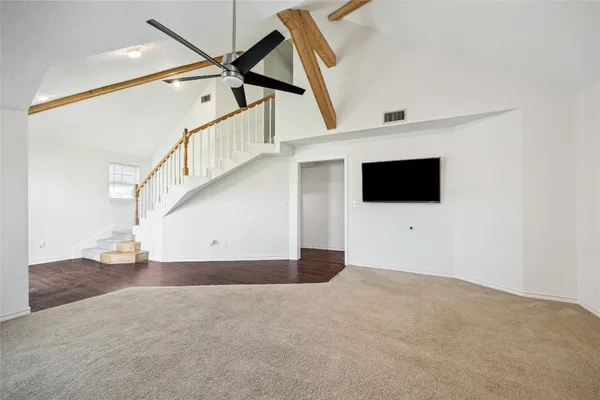 a view of an empty room with wooden floor and a ceiling fan