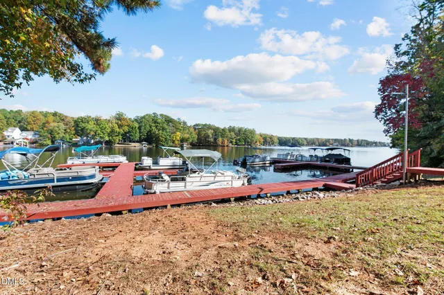 a view of a lake with lawn chairs and a large tree