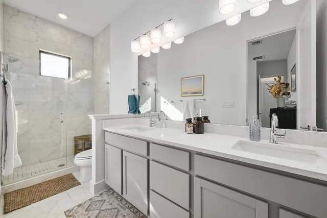a bathroom with a double vanity sink mirror and toilet