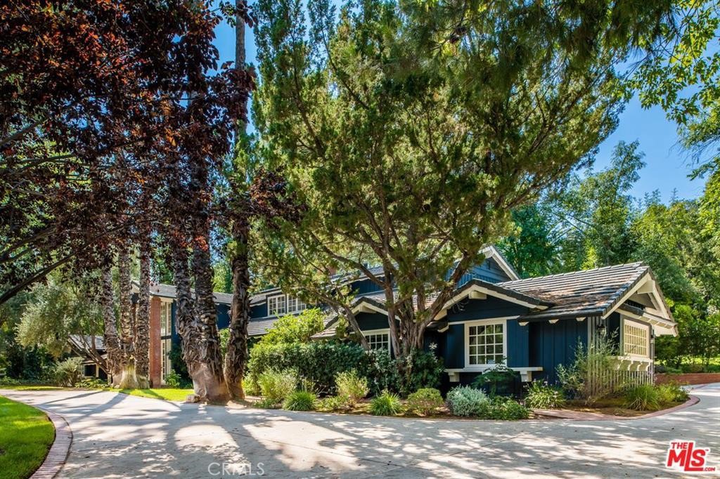 a front view of a house with a yard and large trees