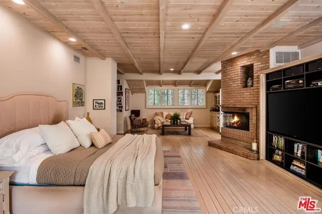 a spacious bedroom with a bed a fireplace and a book shelf