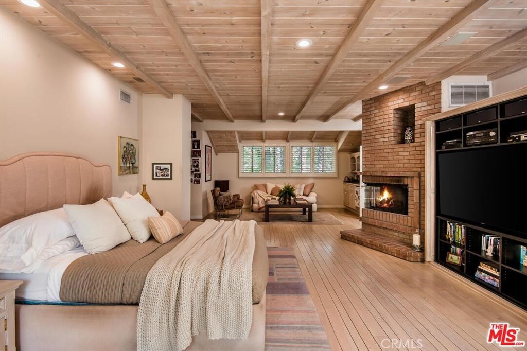 5255 Round Meadow Road Hidden Hills, CA 91302 - Photo 9 of 18 a spacious bedroom with a bed a fireplace and a book shelf