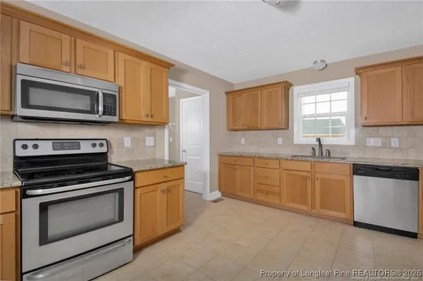 a kitchen with stainless steel appliances granite countertop grey cabinets a stove a sink and dishwasher