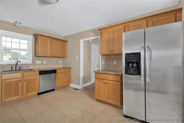 a kitchen with stainless steel appliances granite countertop a refrigerator and a stove top oven