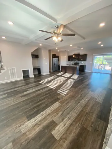 a view of an empty room with kitchen and a window