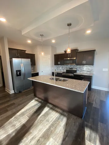 a kitchen with stainless steel appliances granite countertop a sink a stove a refrigerator and a microwave