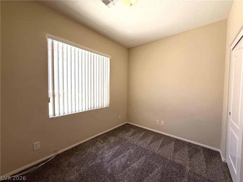 5942 Rampolla Drive Las Vegas, NV 89141 - Photo 17 of 27 A well-lit bedroom features plush patterned carpeting and a window with vertical blinds.