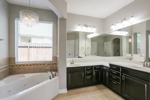 a spacious bathroom with a granite countertop sink a large mirror and a bathtub