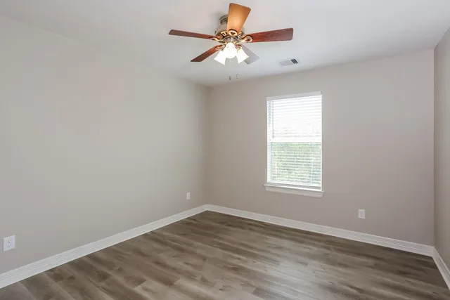 an empty room with a window and a fan