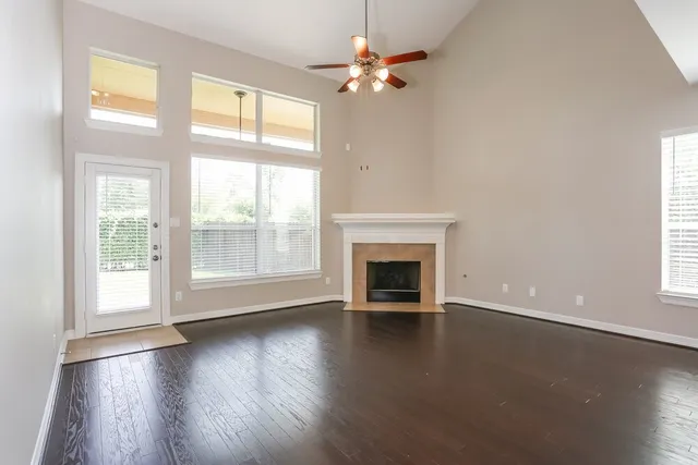 an empty room with wooden floor fireplace and windows