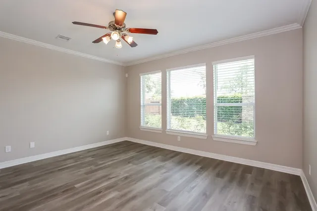 a view of an empty room with window and chandelier fan