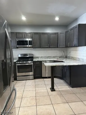a kitchen with stainless steel appliances granite countertop a stove kitchen island a sink dishwasher a refrigerator and a microwave