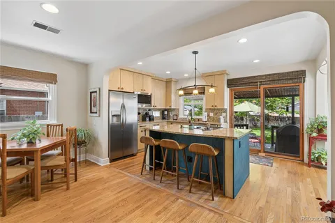 a kitchen with stainless steel appliances granite countertop a table chairs and a refrigerator