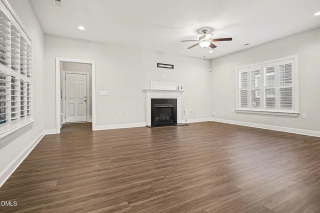 an empty room with wooden floor chandelier and windows