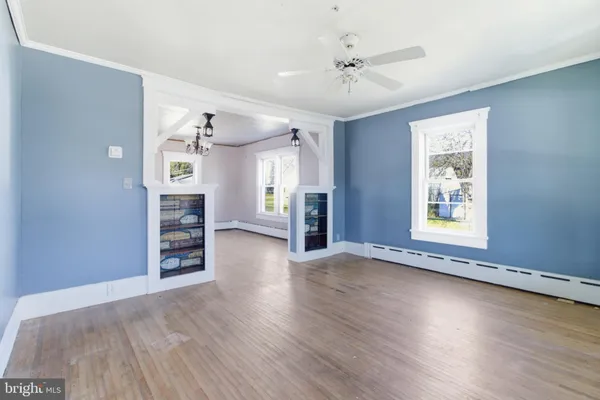 a view of an empty room with a window and wooden floor