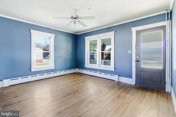 a view of an empty room with a window and wooden floor