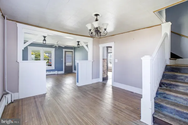 a view of a hallway with wooden floor and a kitchen