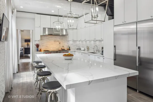 a kitchen with stainless steel appliances kitchen island a table chairs in it and wooden floors