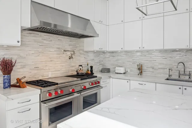 a kitchen with stainless steel appliances a stove and white cabinets