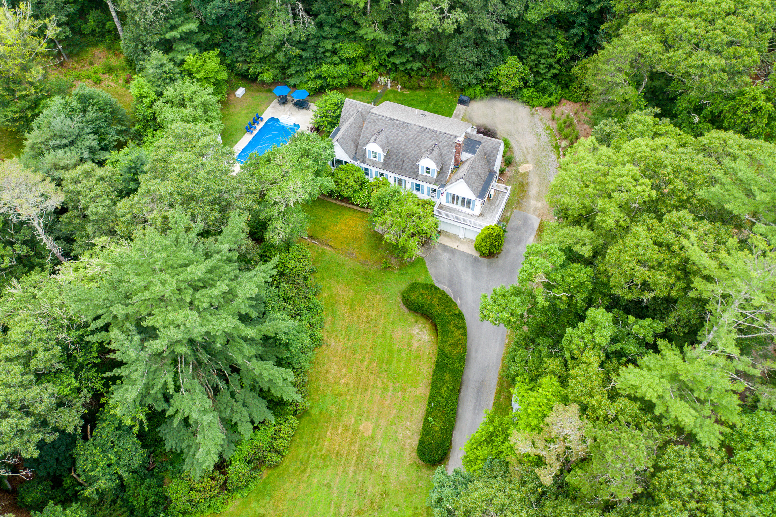 an aerial view of a house with a yard swimming pool outdoor seating and trees