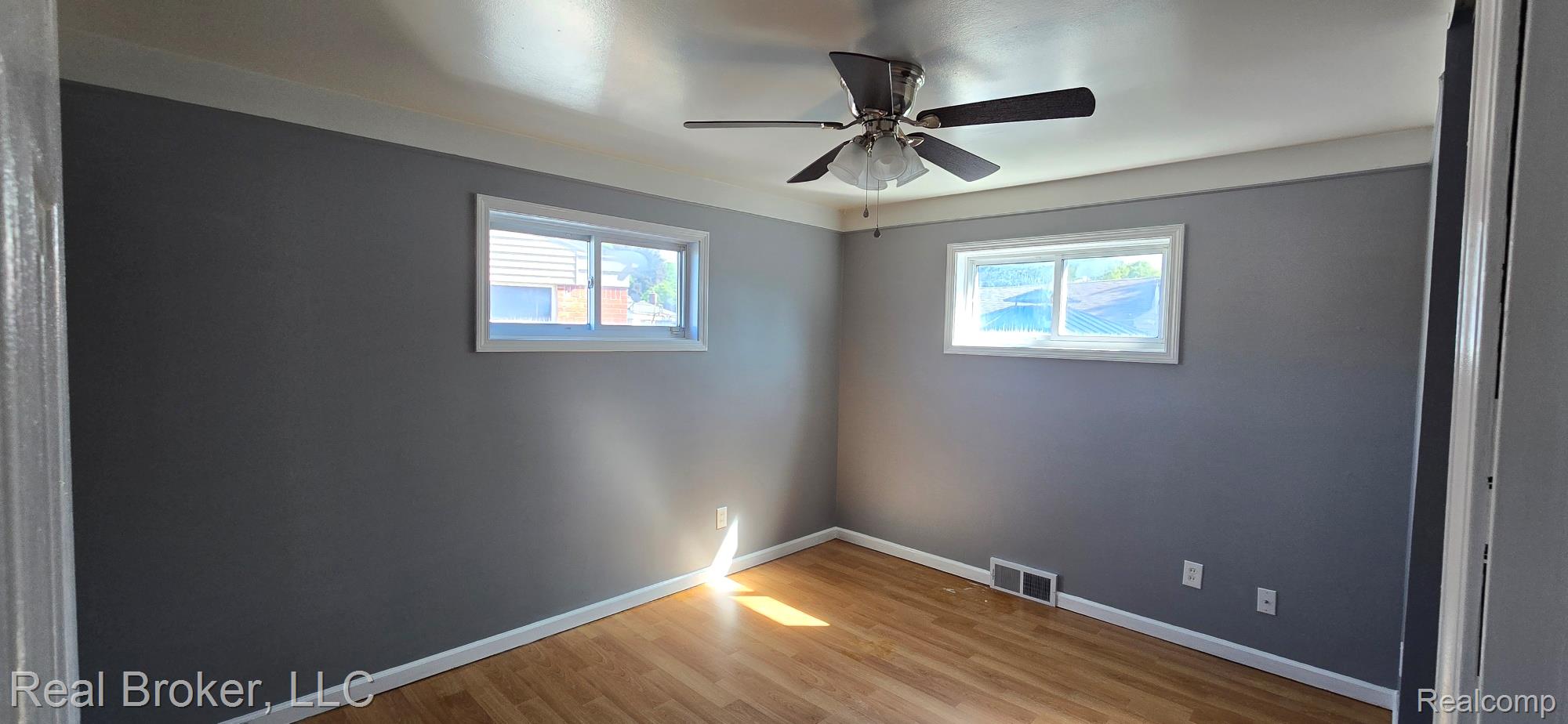 23401 Filmore Street Taylor, MI 48180 - Photo 9 of 16 Room featuring wood-finish flooring, two windows, a ceiling fan with integrated lighting, and gray painted walls with white trim