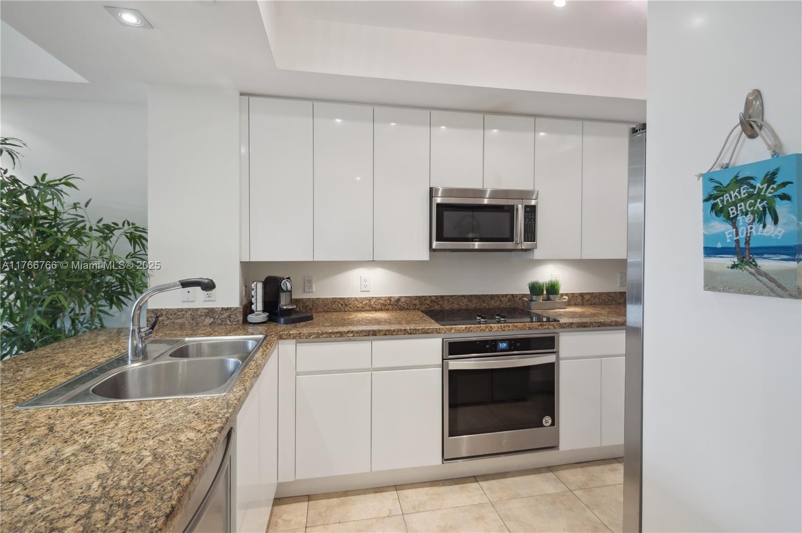 765 Crandon Boulevard, Unit 111 Key Biscayne, FL 33149 - Photo 11 of 57 a kitchen with granite countertop a sink stove and microwave