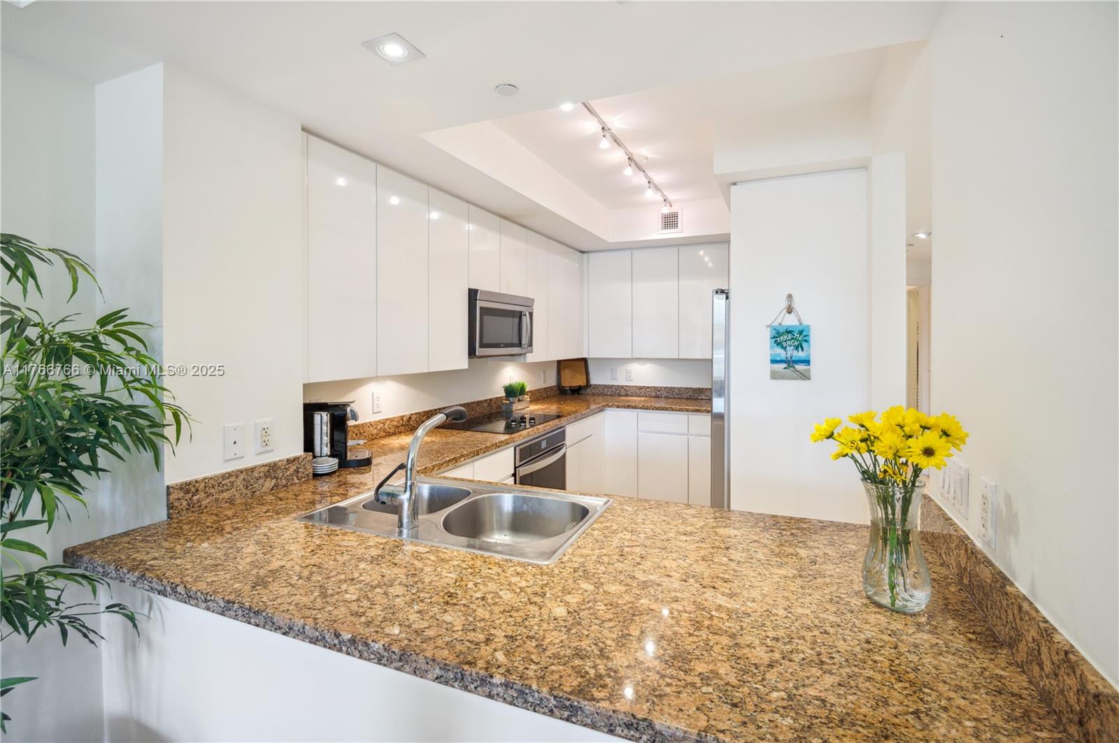 765 Crandon Boulevard, Unit 111 Key Biscayne, FL 33149 - Photo 9 of 57 a kitchen with stainless steel appliances granite countertop a sink a stove a counter top space cabinets and living room view