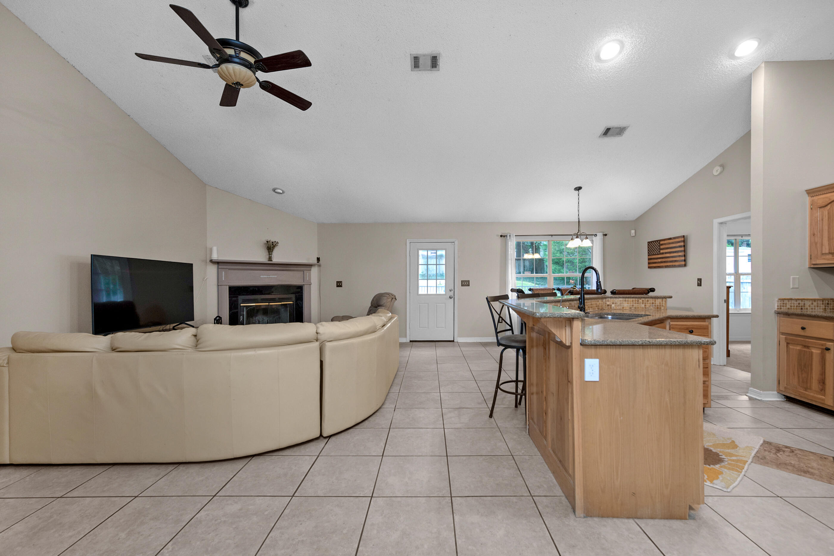 4439 Antioch Road Crestview, FL 32536 - Photo 11 of 32 a living room with a couch a dining table a flat screen tv and kitchen view