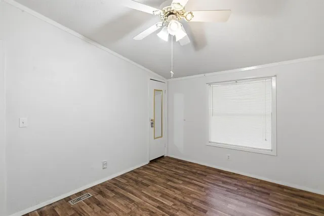 an empty room with wooden floor fan and windows
