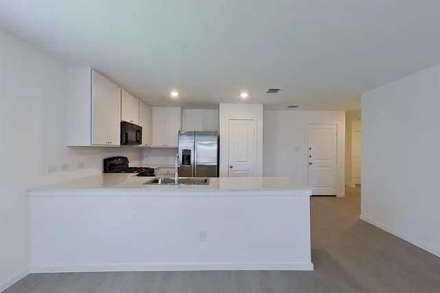 a view of a kitchen with kitchen island stainless steel appliances a sink and a refrigerator