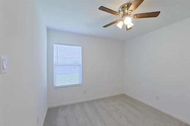 an empty room with a window and a fan