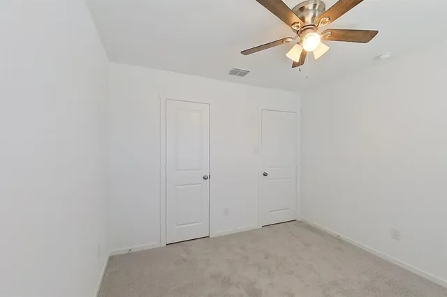 an empty room with a window and a ceiling fan