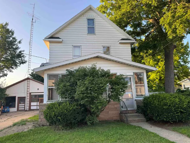 a view of a house with a yard plants and large tree