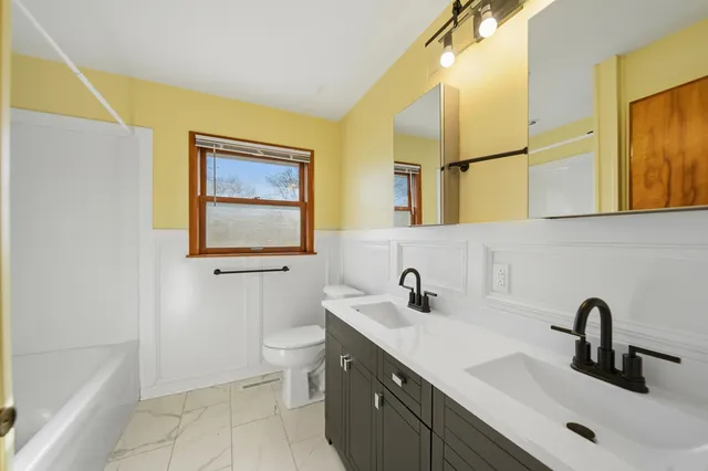 a bathroom with a double vanity sink mirror and bathtub