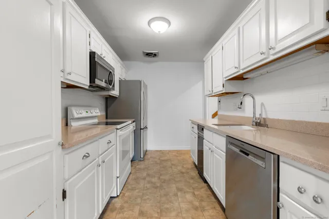 a kitchen with stainless steel appliances granite countertop a sink and dishwasher a stove top oven with white cabinets