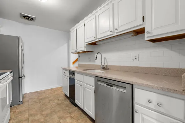 a kitchen with stainless steel appliances granite countertop a sink and a refrigerator