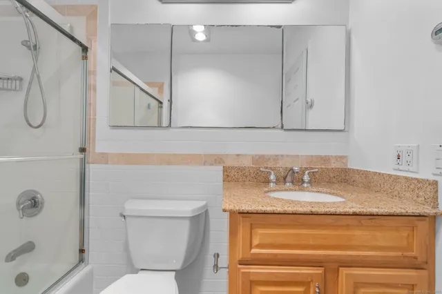 a bathroom with a granite countertop sink toilet and shower